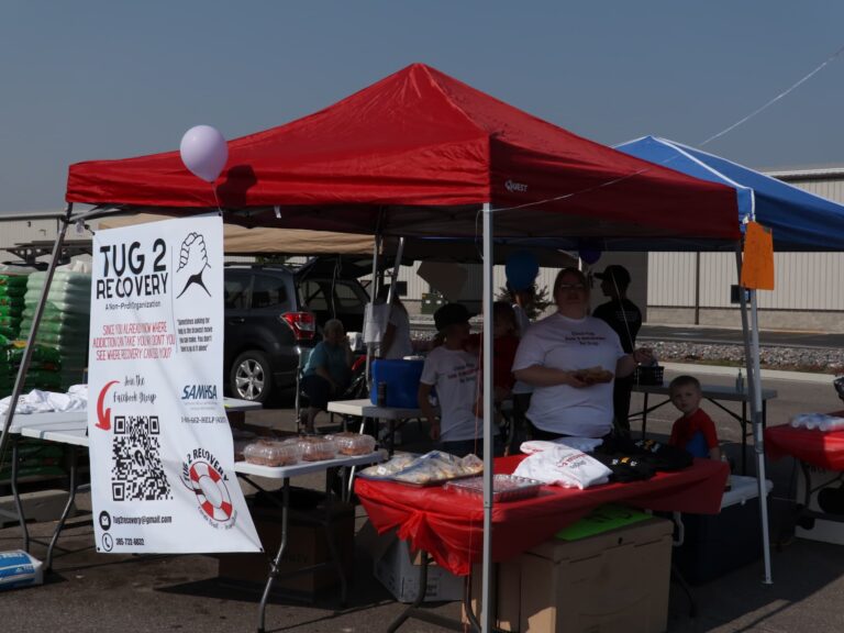Members participating in a community event with tug 2 recovery sign